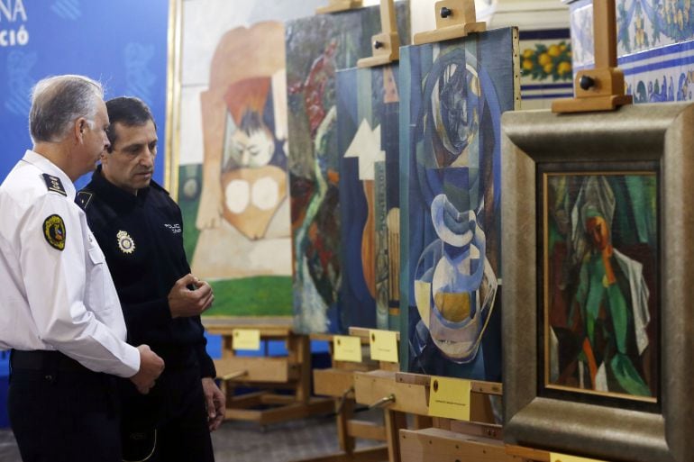 Un policía nacional y un policía autonómico conversan ante las obras falsas de Picasso, por cuya venta ilícita han sido detenidas ocho personas, en una operación de la que ha informado hoy el grupo de patrimonio histórico de la Policía de la Generalitat. 