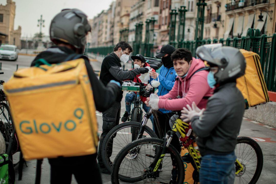 Miembros de la plataforma Riders X Derechos, compuesta por repartidores y mensajeros de Valencia, reparten equipos de protección, especialmente mascarillas, a estos trabajadores, cuya actividad está entre las permitidas por el Gobierno en el estado de alarma.