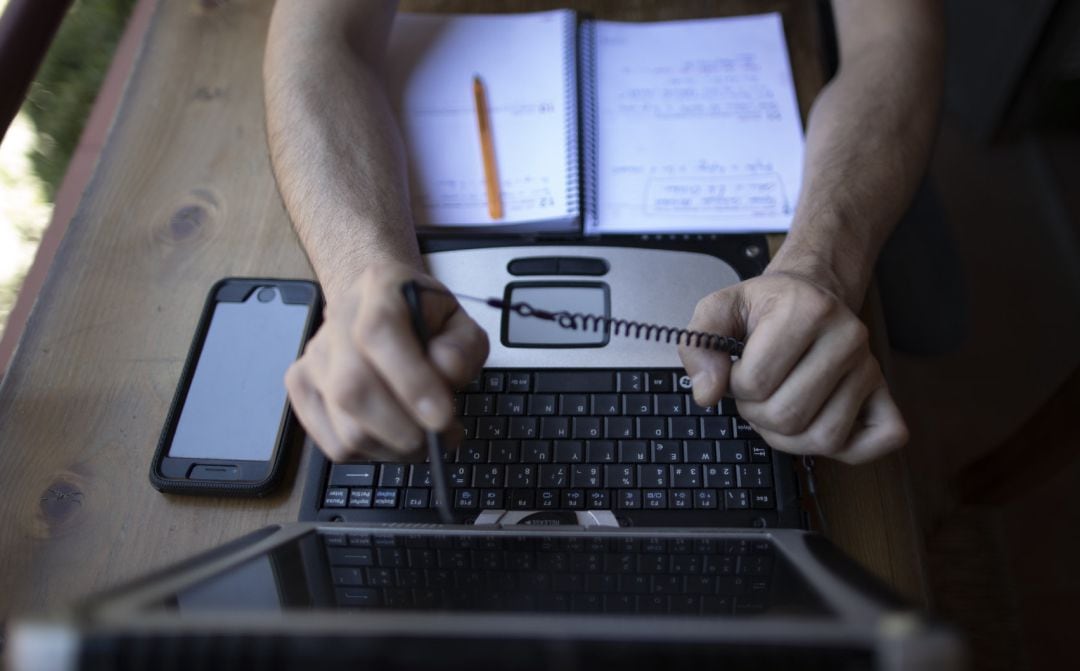 Un hombre teletrabajando desde su casa con un portátil.