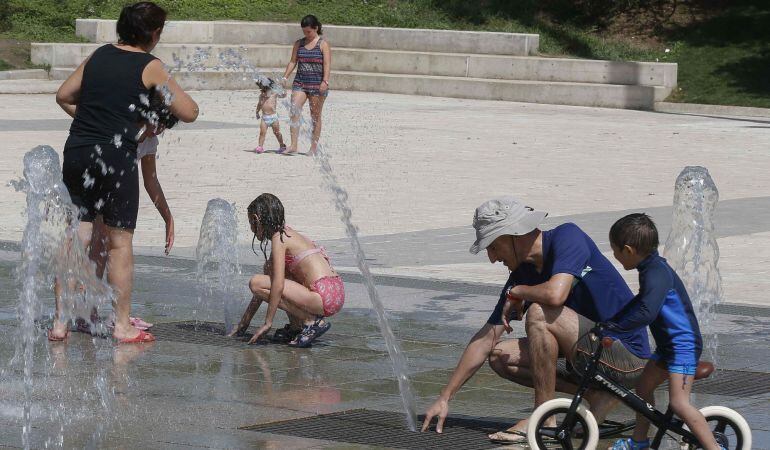 Varias personas se refrescan en las fuentes verticales del parque Juan Carlos I de Madrid.