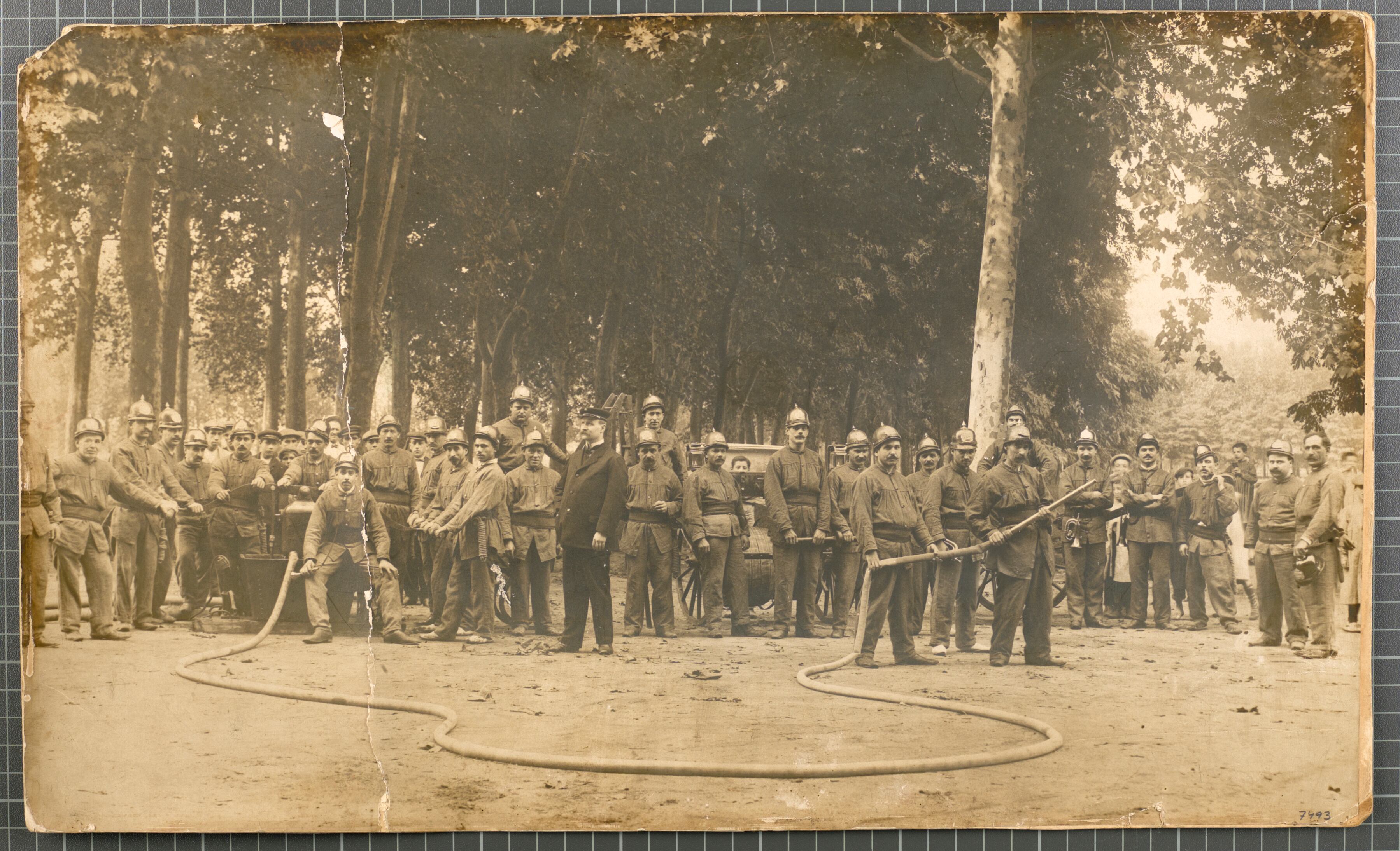 Retrat de grup de la Primera Companyia de Bombers de l&#039;Ajuntament de Girona, amb els seus uniformes i recursos materials per lluitar contra el foc, a la Devesa. Possiblement es tracti d&#039;una de les exhibicions que es portaven a terme durant les fires. 