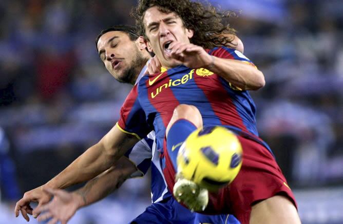 El defensa del F.C. Barcelona Carles Puyol intenta hacerse con un balón ante el delantero argentino del RCD Espanyol Pablo Daniel Osvaldo