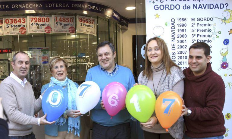 GRA041. BILBAO, 22/12/2014.- Los empleados de la administración de loteria que ha repartido el cuarto premio con el número 07617, posan con los números premiados en globos, en la capital vizcaina durante el tradicional sorteo navideño. EFE/LUIS TEJIDO