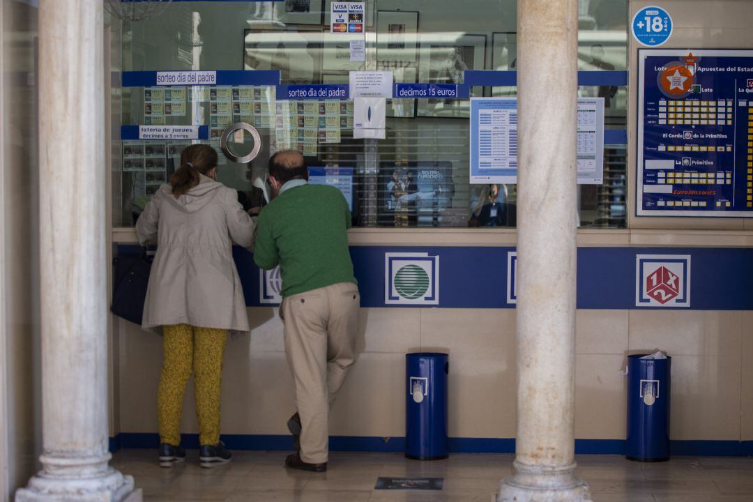 Dos personas compran lotería en una Administración.