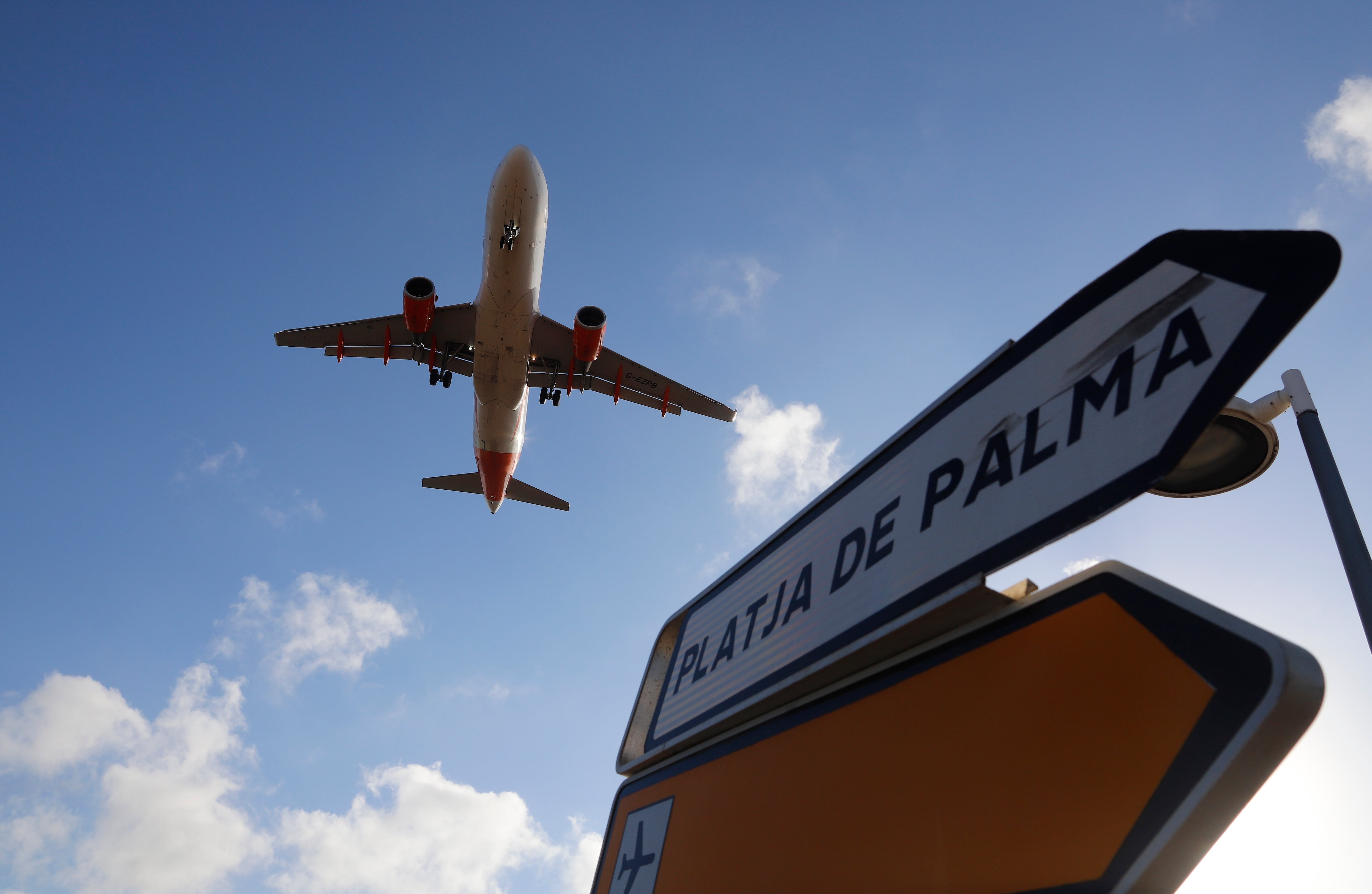 18 August 2020, Spain, Palma: When landing on Mallorca, a plane flies over a sign indicating the direction to Playa de Palma. On Friday the German Foreign Office had issued a travel warning for almost all of Spain. It also applies to the Balearic Islands including the most important destination Mallorca. Photo: Clara Margais/dpa (Photo by Clara Margais/picture alliance via Getty Images)