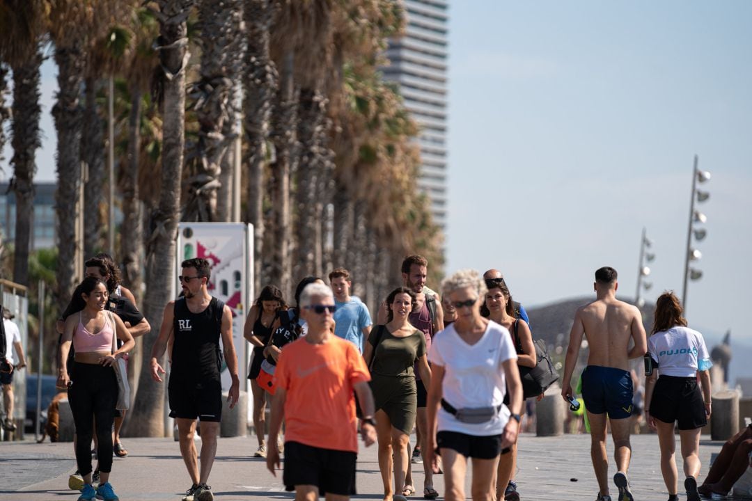 Un grupo de personas pasea por la Barceloneta.