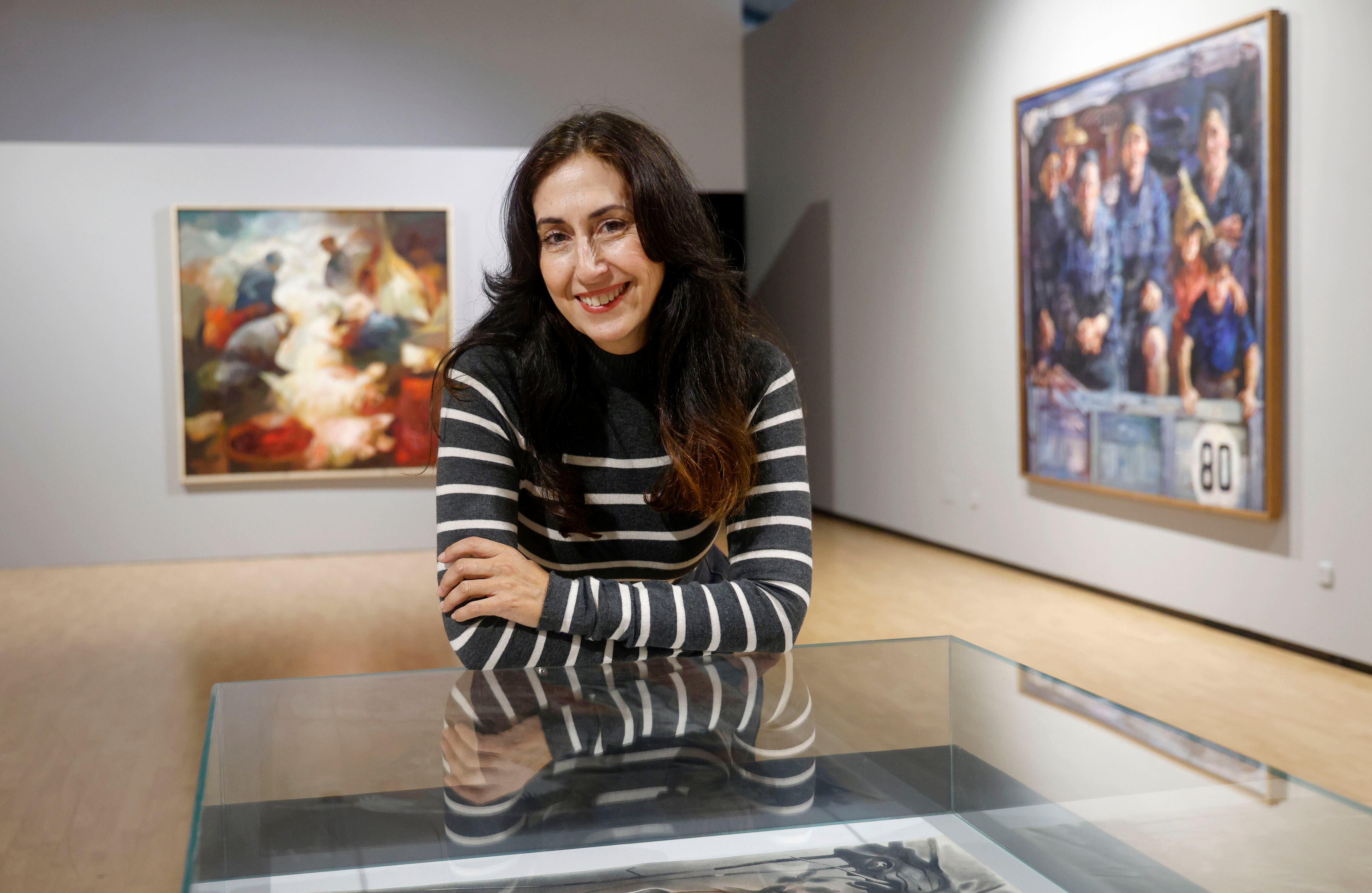 Helena, hija del pintor ferrolés Ricardo Segura Torrella, posa ante obras de su padre que forman parte de la retrospectiva (foto: Kiko Delgado / EFE)