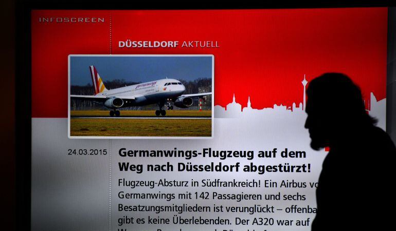 Un hombre camina frente a un cartel en el aeropuerto de Düsseldorf.