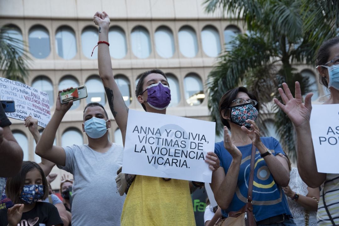 Un mujer con un cartel en el que se lee: `Anna y Olivia, víctimas de violencia vicaria´, participa en una concentración feminista en Tenerife.