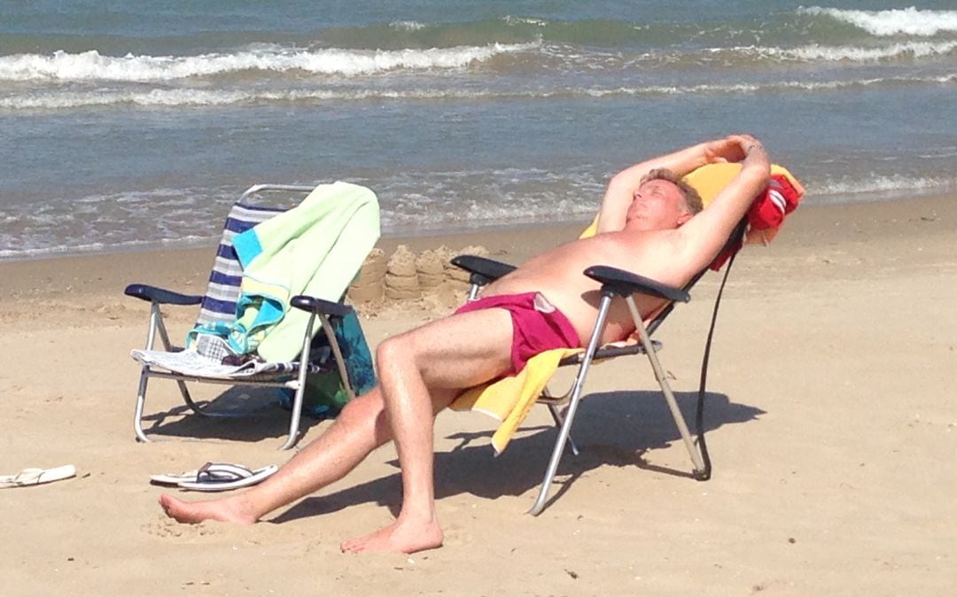 Un hombre tomando el sol en la playa.