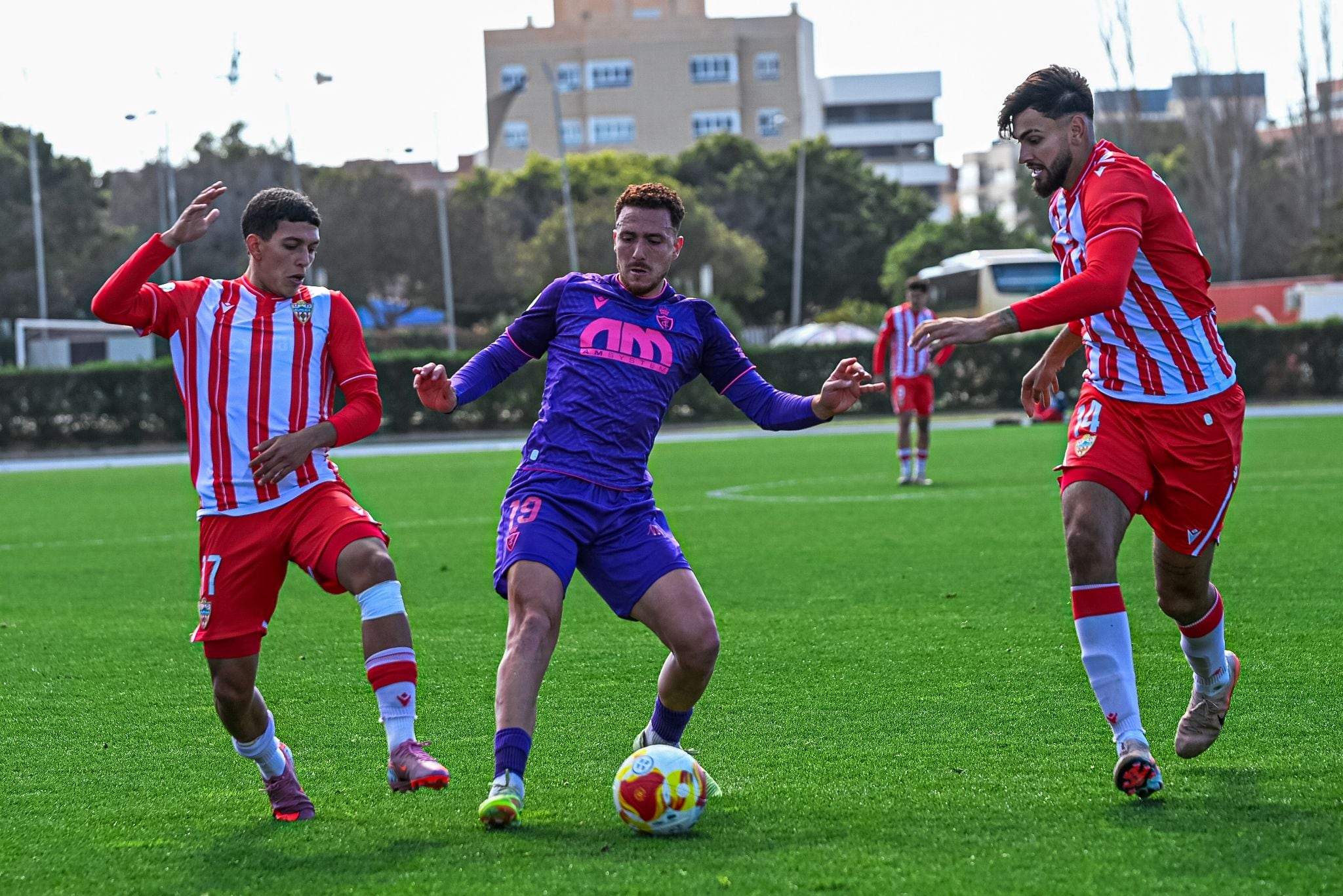 El futbolista del Real Jaén, Agus Alonso, entre dos jugadores del Almería B, durante el partido.
