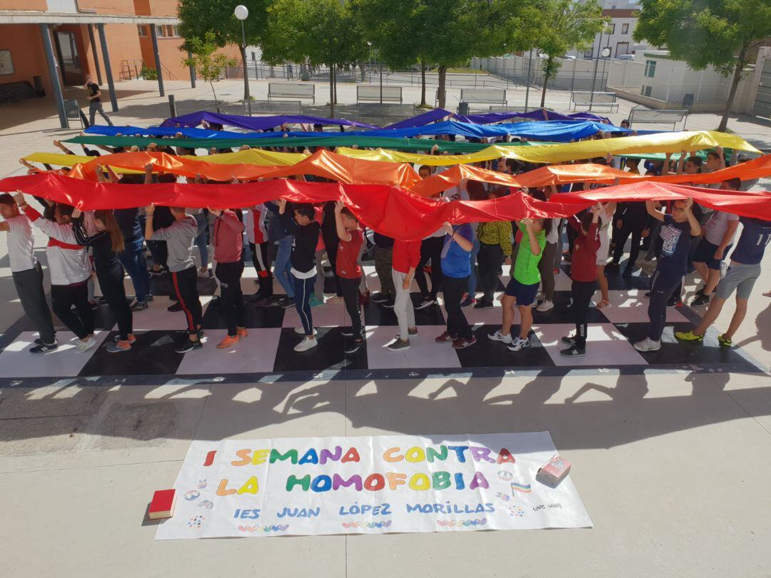 Momento en que alumnos y alumnas desplegan la bandera arcoiris