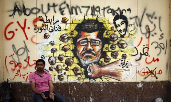 Un manifestante ante un &#039;graffiti&#039; contra Mursi en el Palacio Presidencial de El Cairo