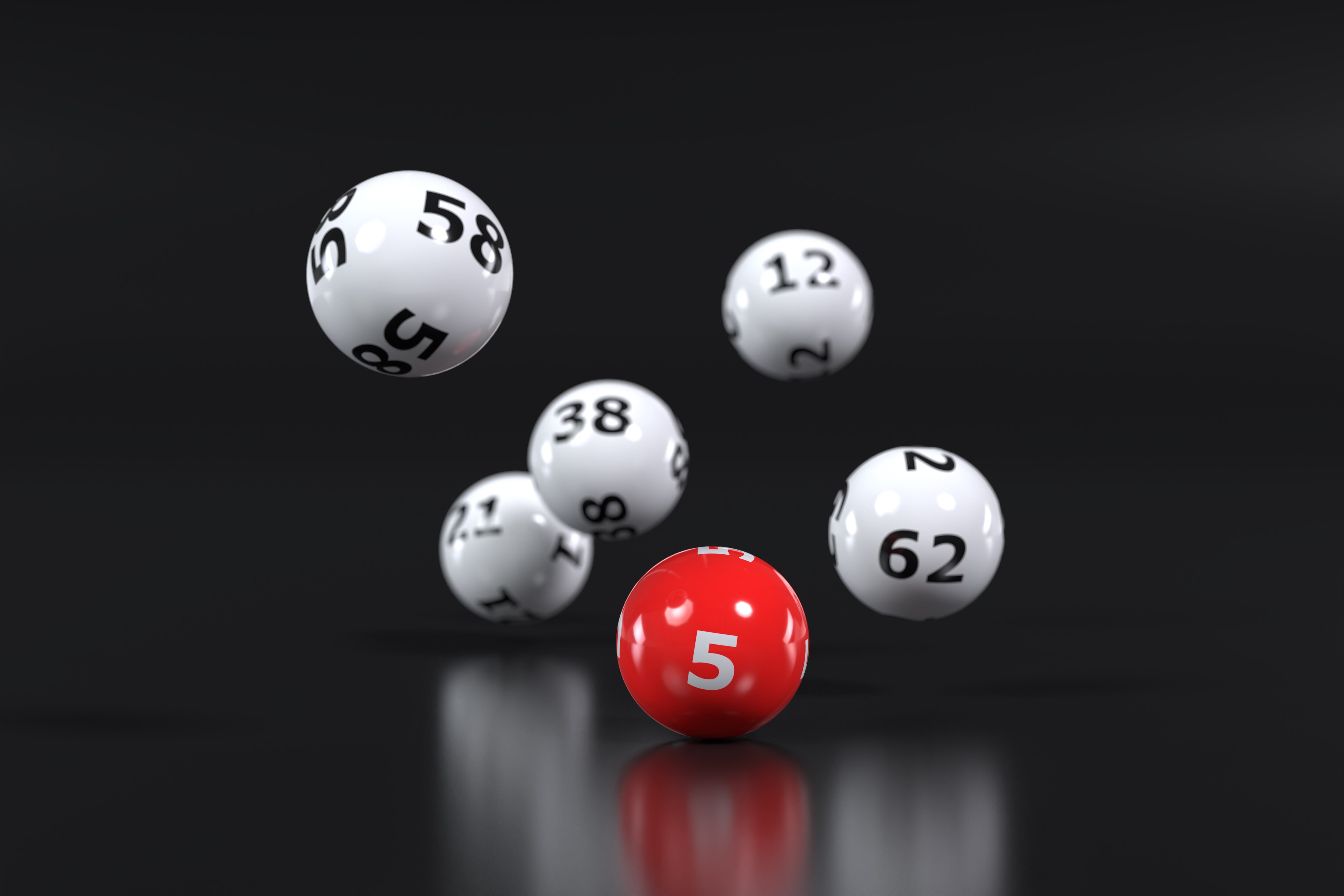 Six falling lottery balls with random numbers on a dark background