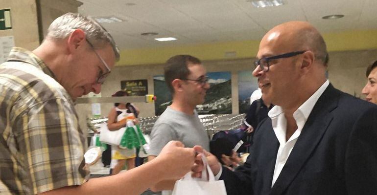 El diputado de Promoción y Turismo, Manuel Fernández, entrega una bolsa promocional a uno de los pasajeros del vuelo Berlín-Granada-Jaén.