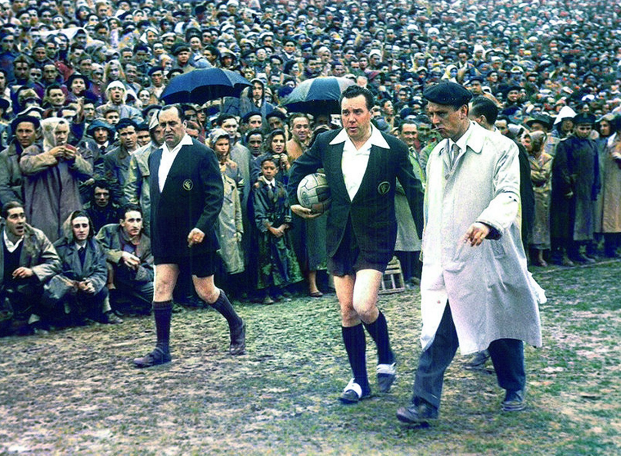 El arbitro y el delegado del Alavés Miguel Rotaetxe, recorren el terreno de juego / Archivo de Álava / A. S. Koch / foto coloreada