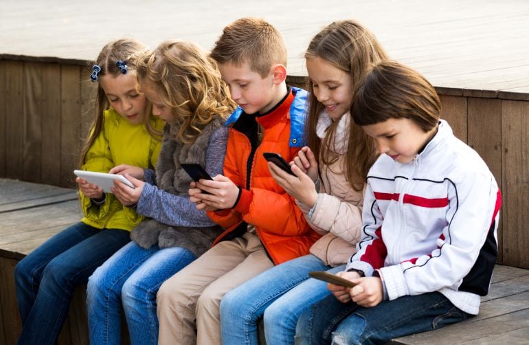 Un grupo de chicos utiliza tabletas y teléfonos móviles. 