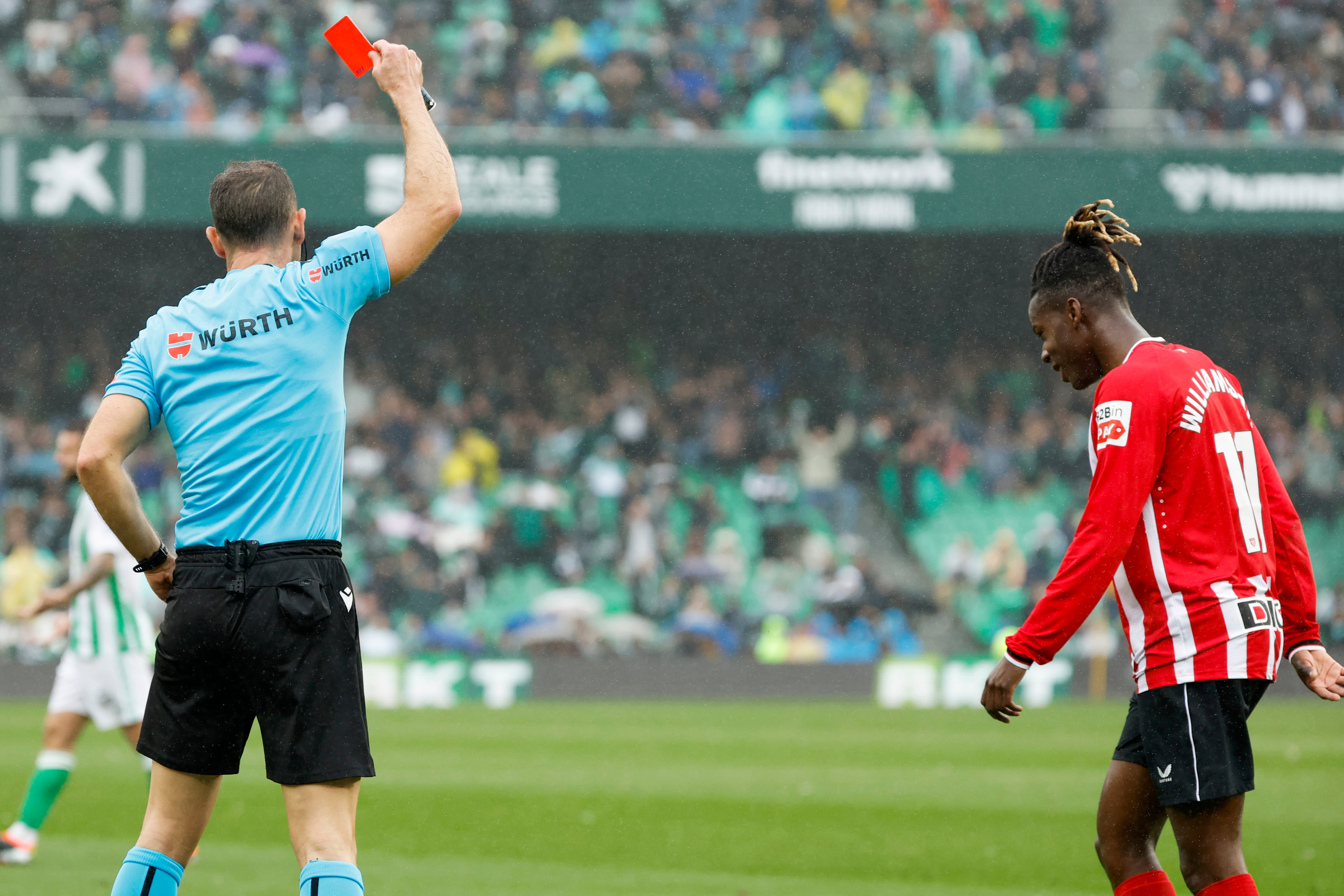 El delantero del Athletic Nico Williams (d) recibe una cartulina roja durante el partido de la Jornada 26 de LaLiga que Betis y Athletic disputan este domino en el estadio Benito Villamarín