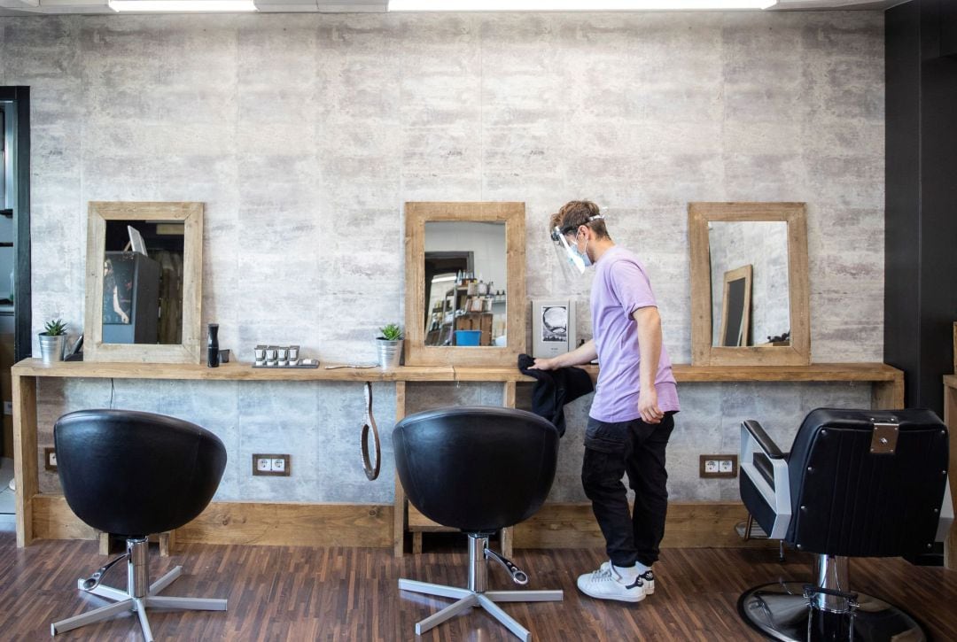 Un empleado desinfecta con una disolución de lejía y agua la zona de corte, durante la visita a la peluquería Akaba Salón en Madrid, donde hoy han realizado las labores de limpieza y desinfección y han mostrado las nuevas medidas de protección e higiene para la reapertura el próximo lunes 4 de mayo.