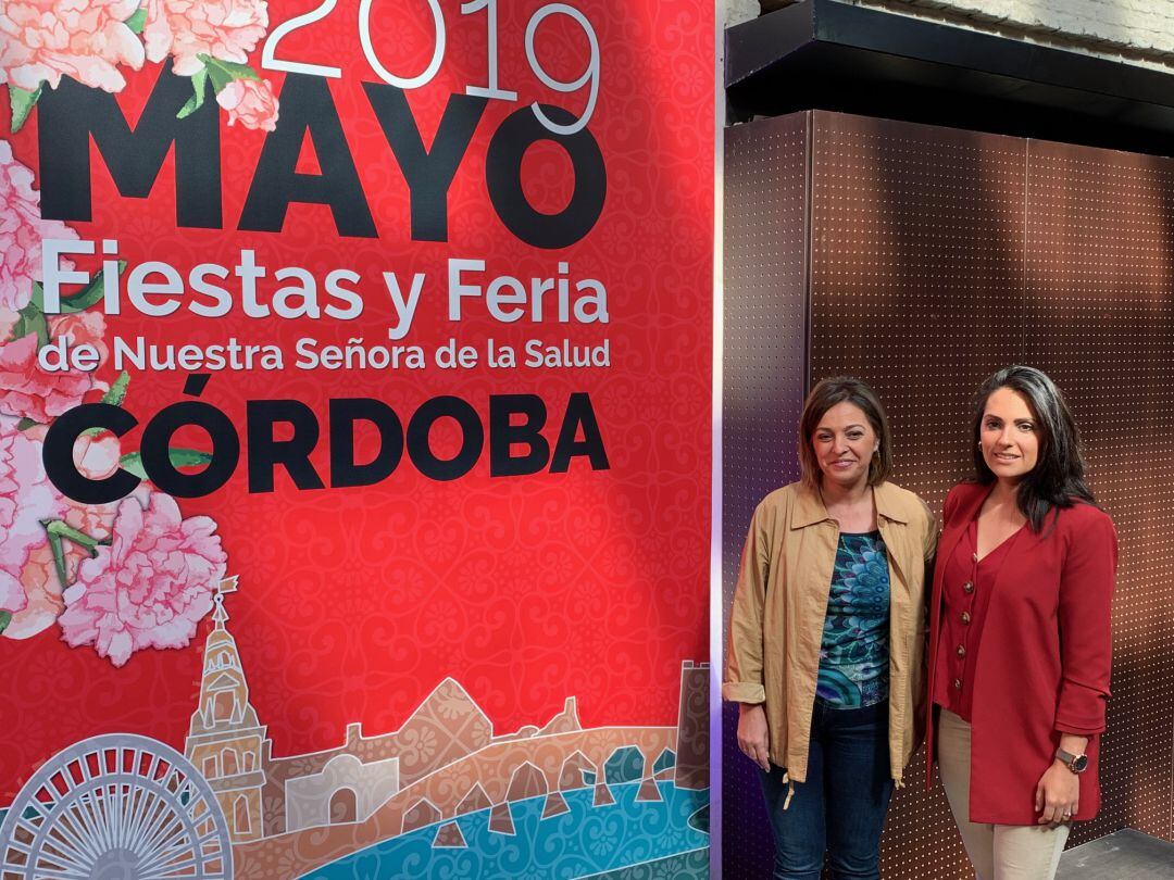 Isabel Ambrosio y Carmen González posan junto al cartel de este año