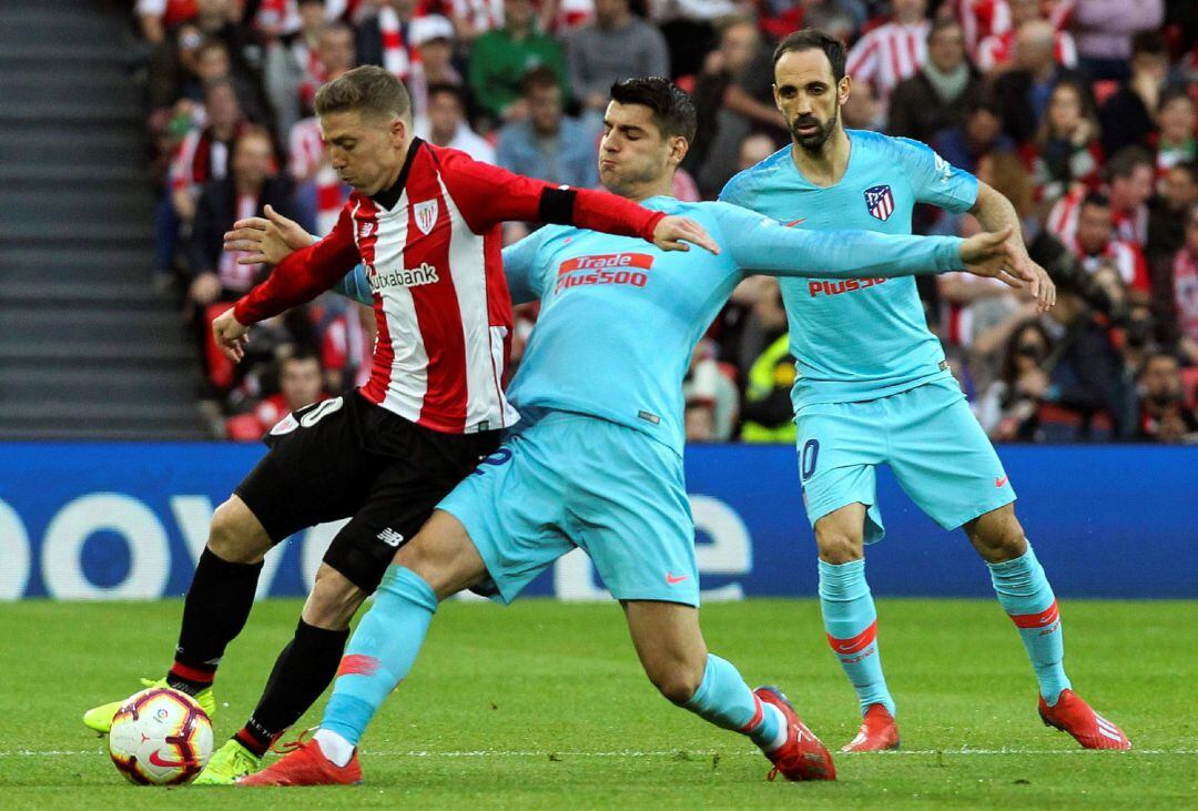 El centrocampista del Athletic, Iker Muniain (i), intenta llevarse el balón ante el acoso del delantero del Atlético de Madrid, Álvaro Morata, durante el encuentro correspondiente a la jornada 28 de primera división que disputan esta tarde en el estadio de San Mamés, en Bilbao