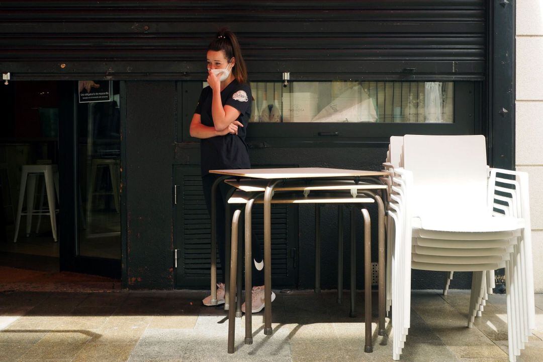 Una trabajadora junto al local en el que trabaja cerrado 