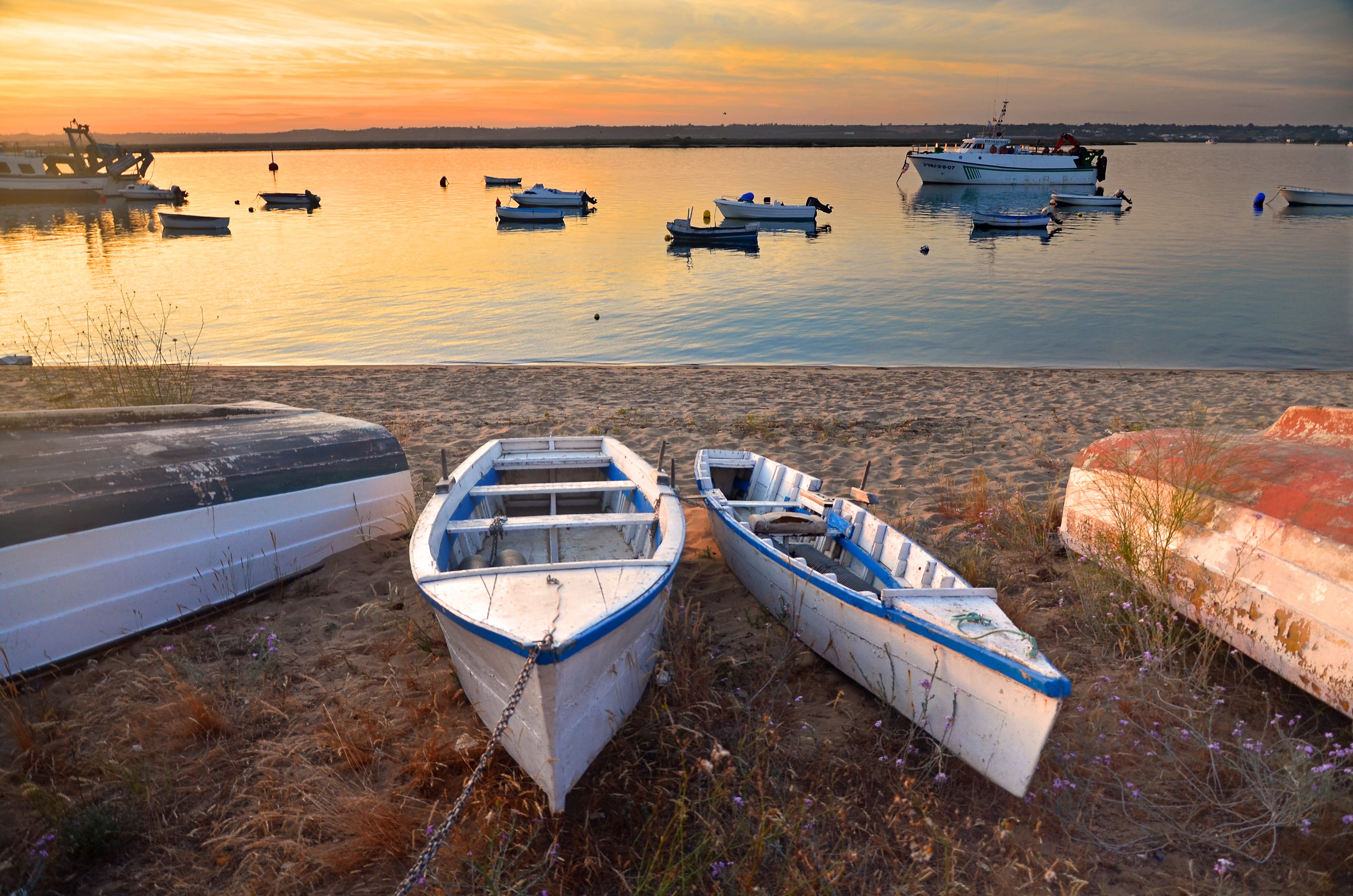 Boats moored on the beach of El Cantil, Isla Cristina, Huelva, during a beautiful sunset.Isla Cristina is one of the most important fishing ports in Andalusia and is famous for its seafood culture and gastronomy, as well as for its beautiful beaches.