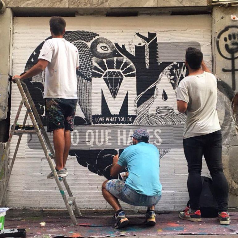 Integrantes del grupo de arte urbano, restaurando el mural de la calle Huertas.