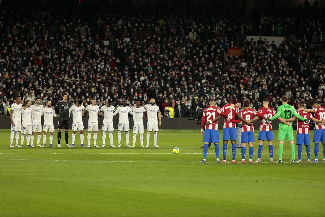 El equipo titular del Madrid y del Atlético, durante el minuto de silencio antes del derbi madrileño