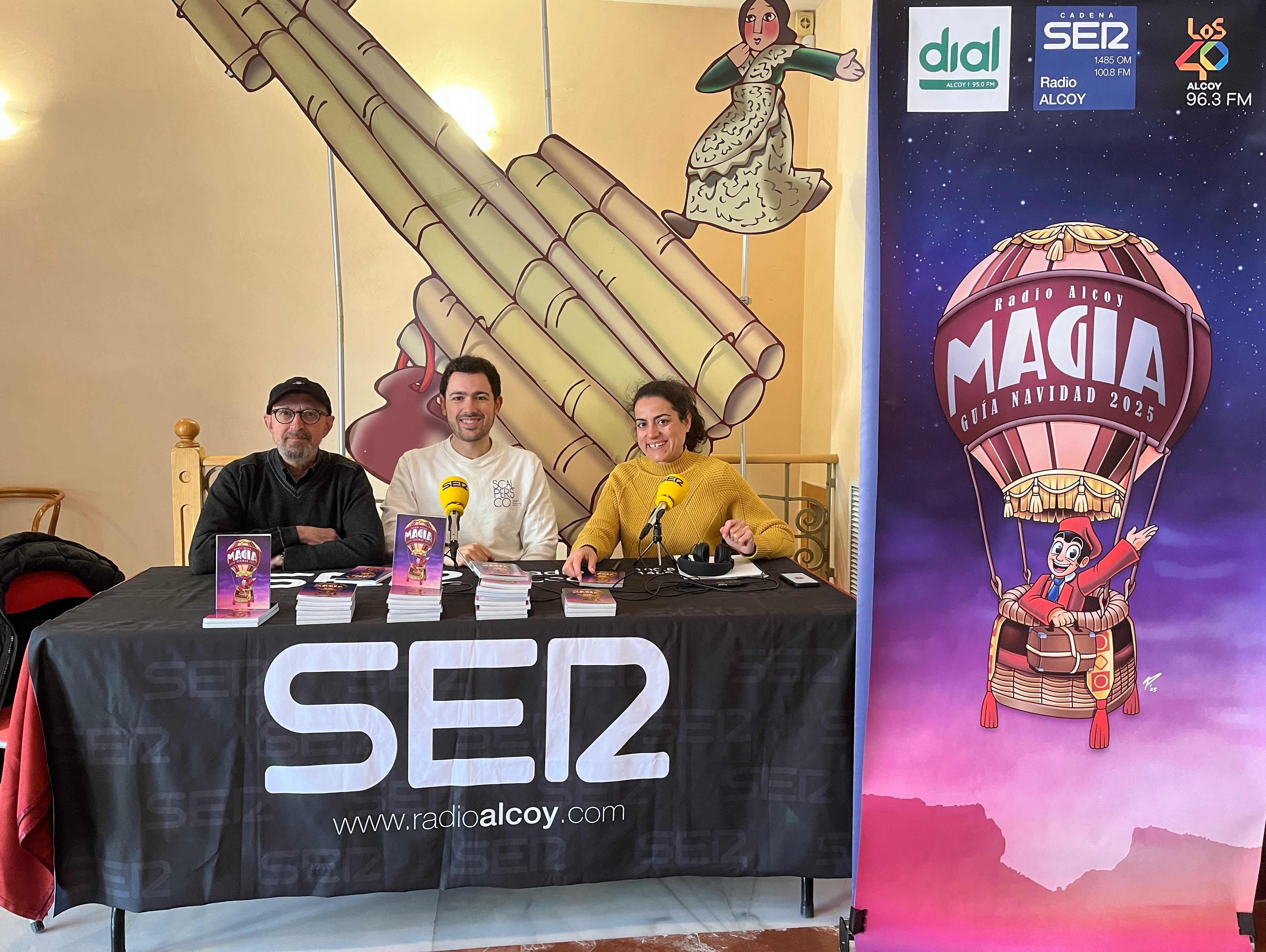 Joanfra Rozalén, gerente de La Dependent; Pablo Sempere, autor de la portada de Magia 2025 y Maribel Vicedo durante la presentación de la novena edición de la guía de Navidad de Radio Alcoy.