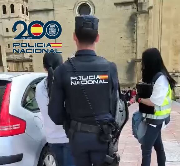 Policía nacional acompañando a una de las mujeres que explotaba sexualmente la organización criminal desarticulada en Parla y Oviedo.