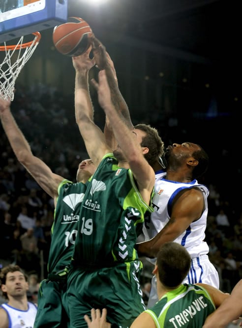 El pívot estadounidense del Real Madrid, D&#039;or Fischer (d), salta a por un rebote ante la oposición del alero Carlos Jiménez (i) y el pívot inglés Joel Freeland (c), del Unicaja Málaga, durante el partido correspondiente a la décima jornada de la Liga ACB