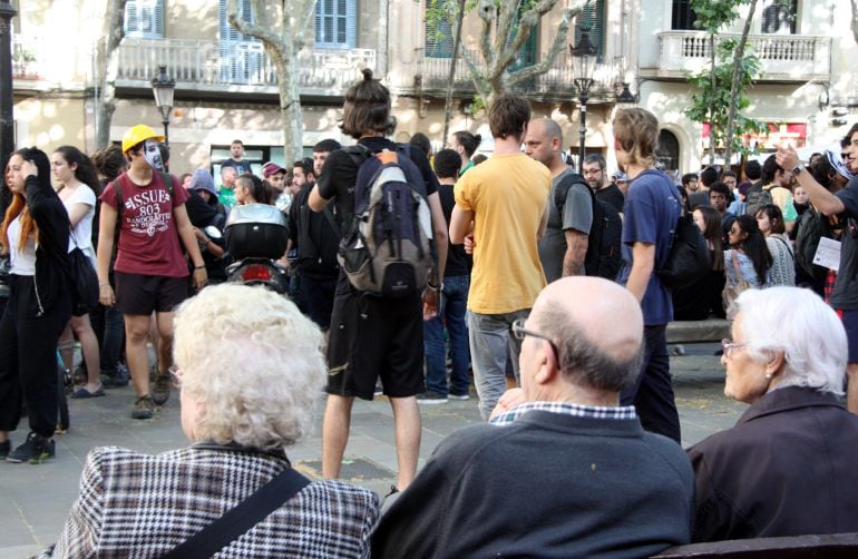 Tres persones grans assegudes a un banc de la plaça Rovira i Trias, al barri de Gràcia.