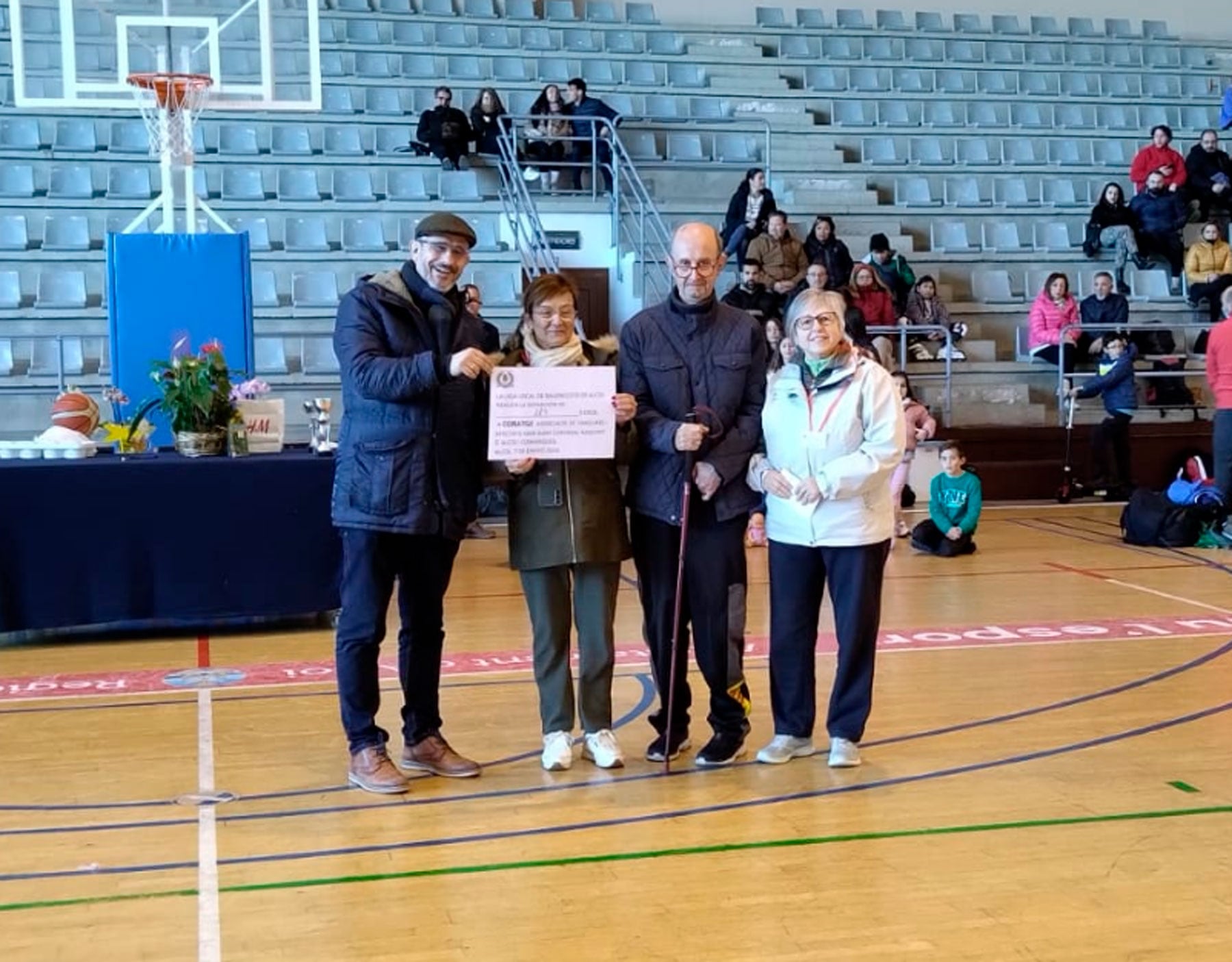 El vicepresidente de la liga local, Javi Fernández, entrega el cheque por valor de 117 euros a representantes de la asociación Coratge