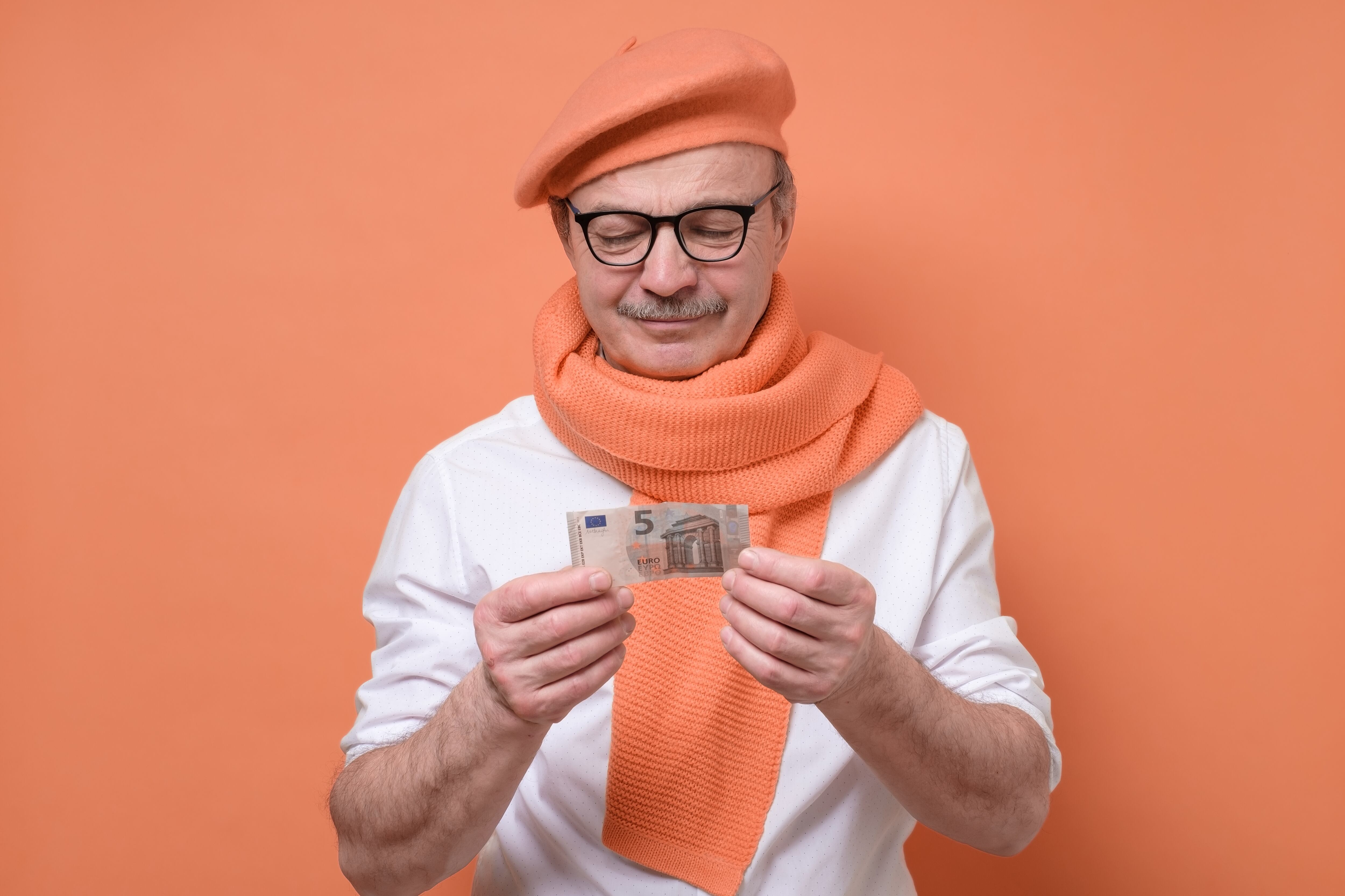 Senior man holding euro bank note stressed being confused and frustrated. It is his last money. Studio shot.