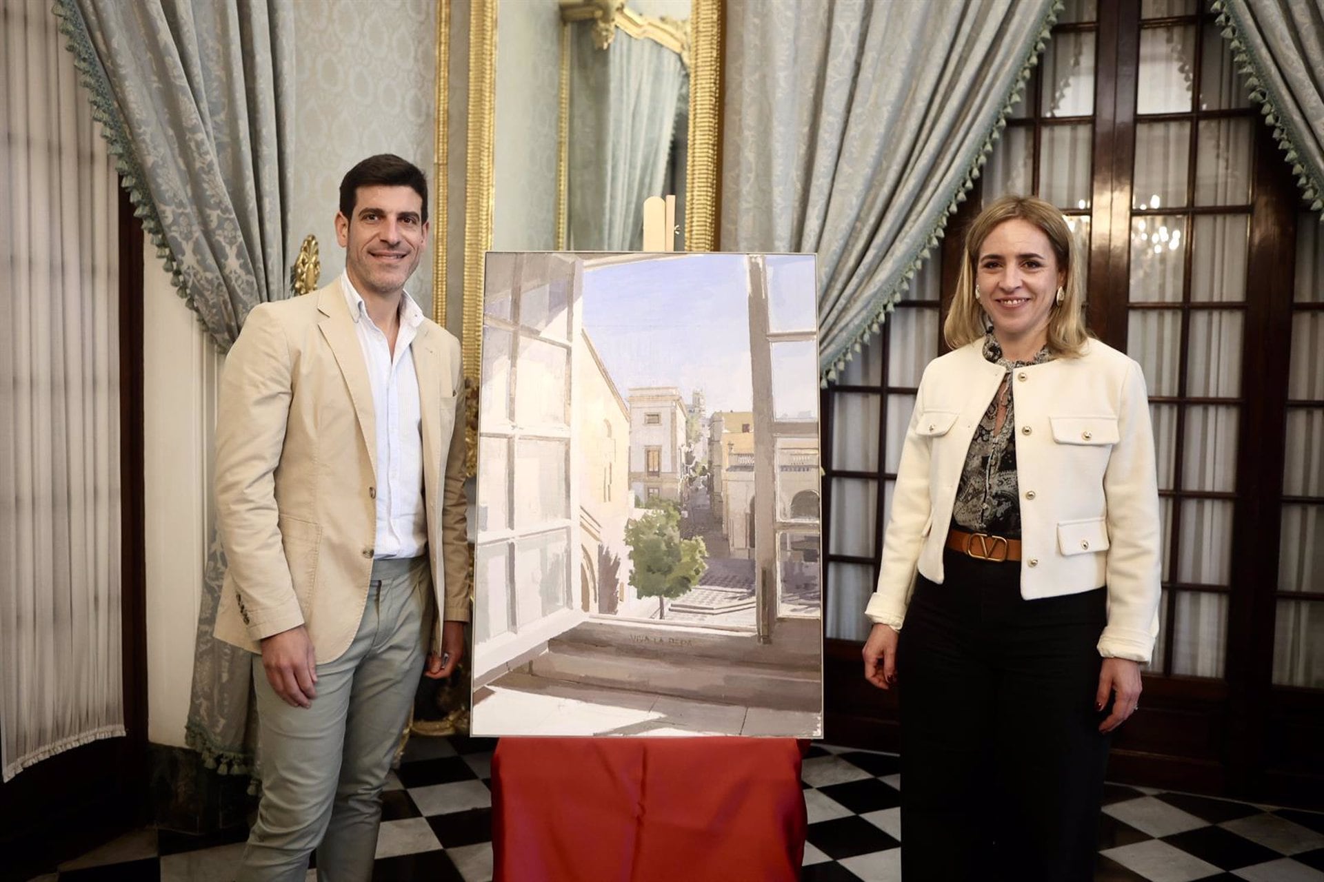 La presidenta de la Diputación de Cádiz, Almudena Martínez, junto al pintor jerezano, Eduardo Millán, presentando el cuadro para el Día de la Provincia