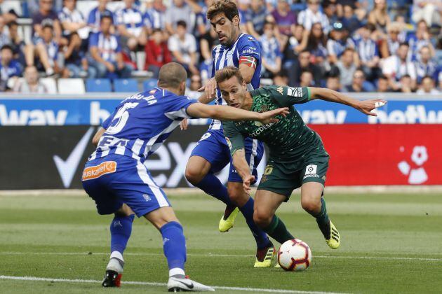 El centrocampista del Betis, Sergio Canales (i), intenta escaparse de los jugadores del Alavés, el defensa Víctor Laguardia (i) y el entrocampista Manu García (c), durante el partido correspondiente a la segunda jornada de Laliga Santander disputado hoy en el campo Mendizorroza de Vitoria.