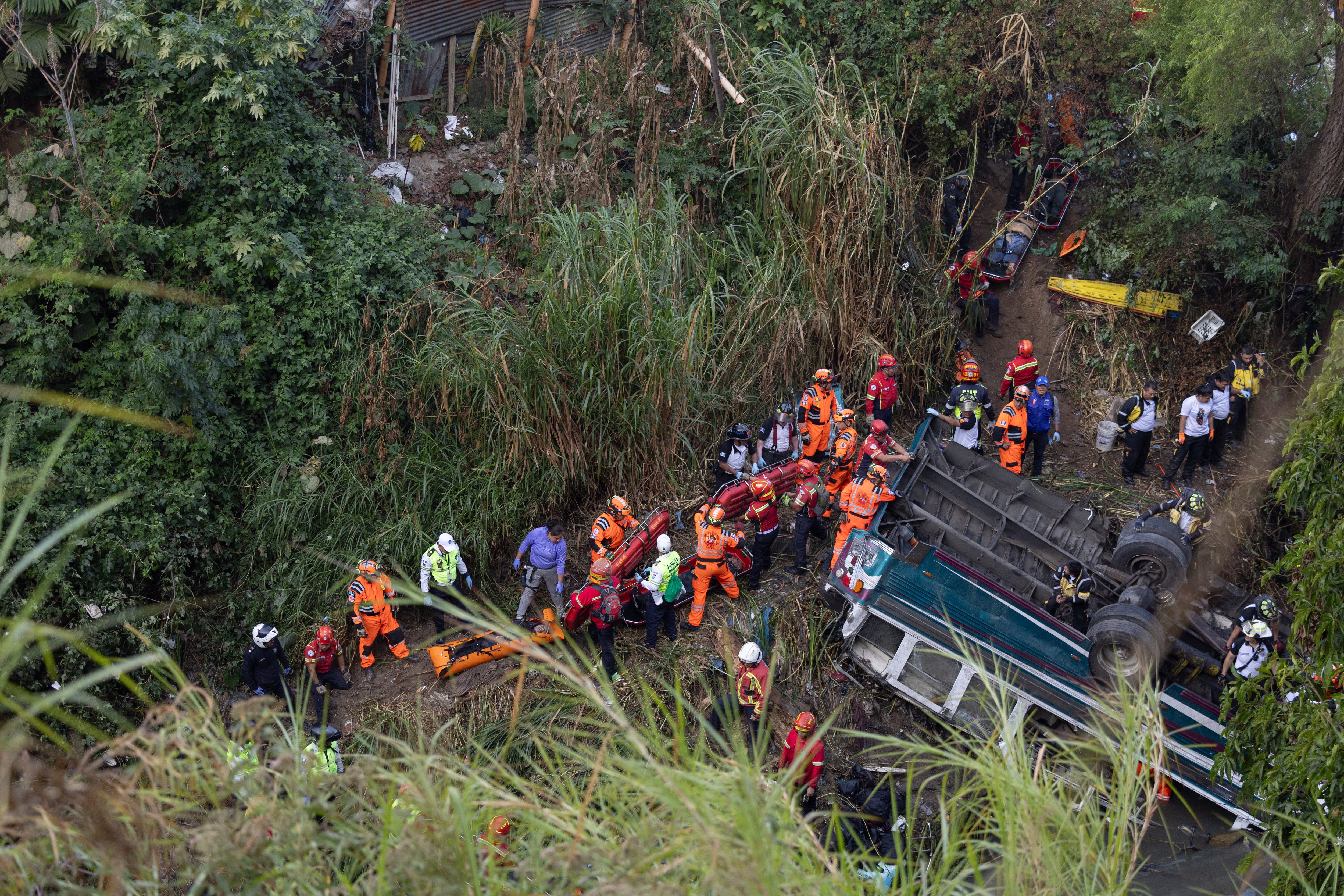 Integrantes de organismos de socorro trabajan en la zona donde ocurrió el accidente de un autobús, que cayó en un río de aguas residuales en el norte de la Ciudad de Guatemala (Guatemala)