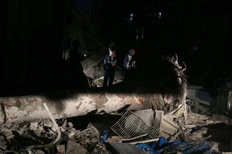 Dos niños inspeccionan uno de los lugares dañados por los bombardeos del ejército sirio en el barrio de al Qaterji en Aleppo