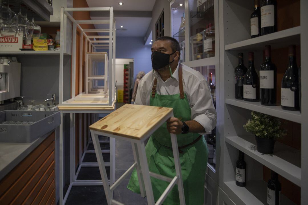 Un hostelero recoge el mobiliario de la terraza de un bar, 