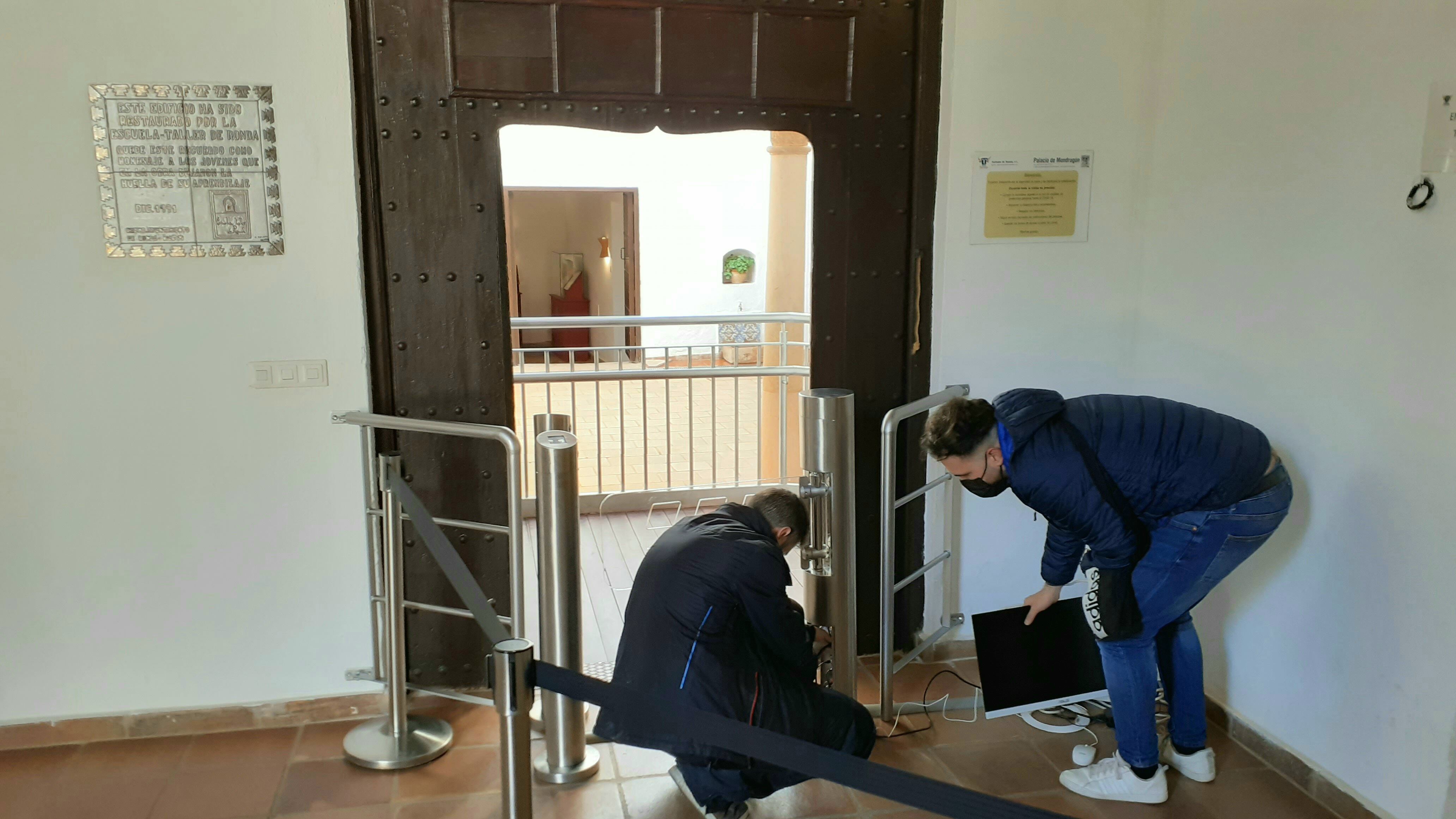 Dos operarios revisan uno de los controles de acceso digitales instalados en algunos monumentos de Ronda