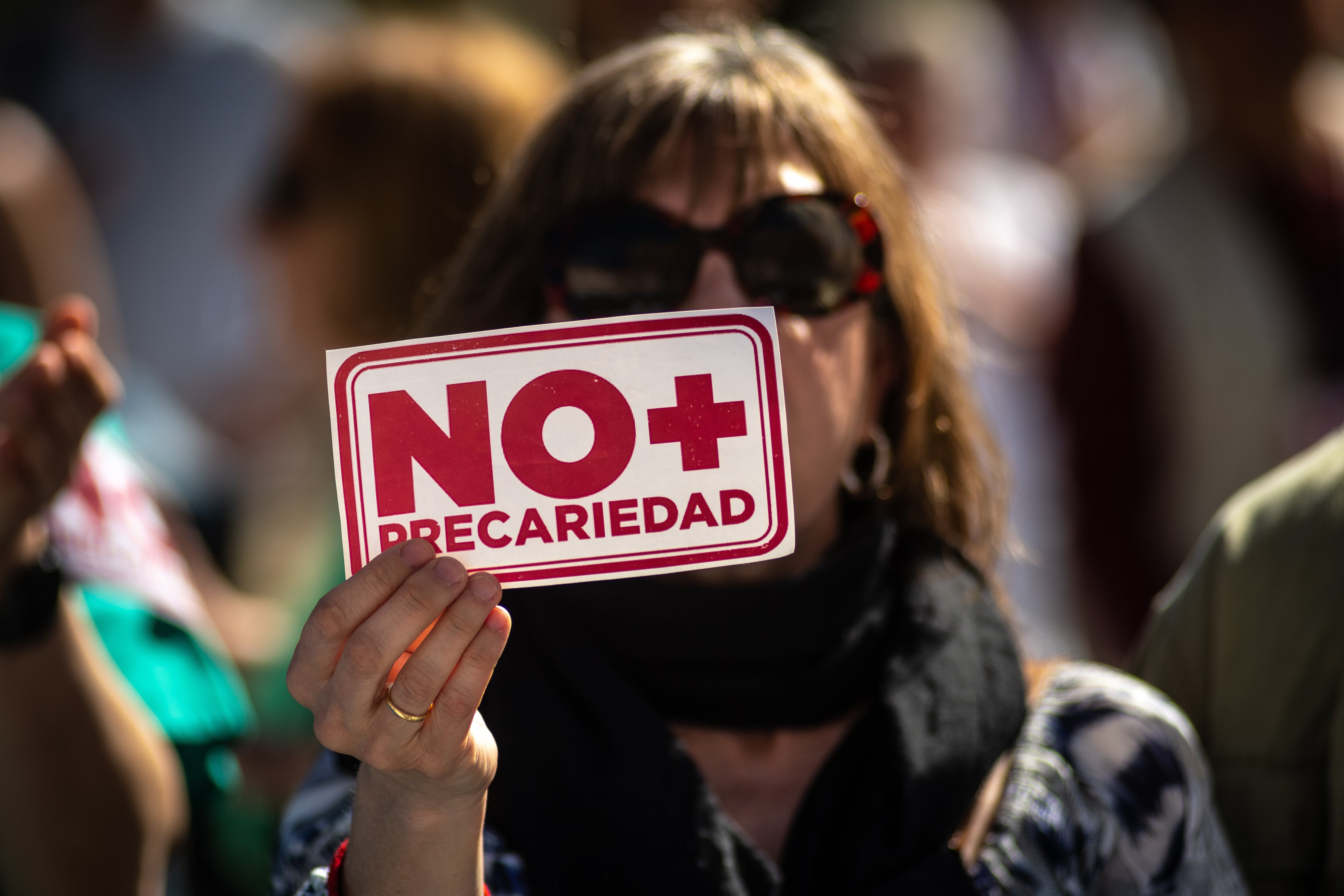 Una mujer sujeta una pegatina de &quot;no más precariedad&quot; en una manifestación de Madrid