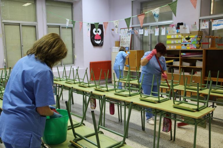 Tres mujeres realizan el trabajo de limpieza en el aula de un colegio