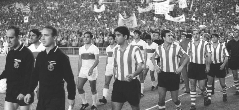 Las formaciones del Elche y el Athletic de Bilbao saltan al terreno de juego del Bernabéu junto al trío arbitral, para disputar la final de la Copa del Generalísimo del año 1969. En primer término, el árbitro Camacho, y los bilbaínos Echeberría y Uriarte.