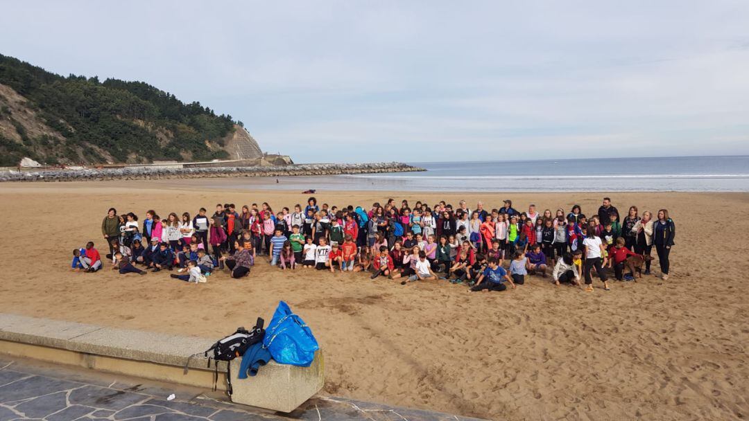 Alrededor de 150 escolares, con profesores y responsables municipales posan en la playa de Deba