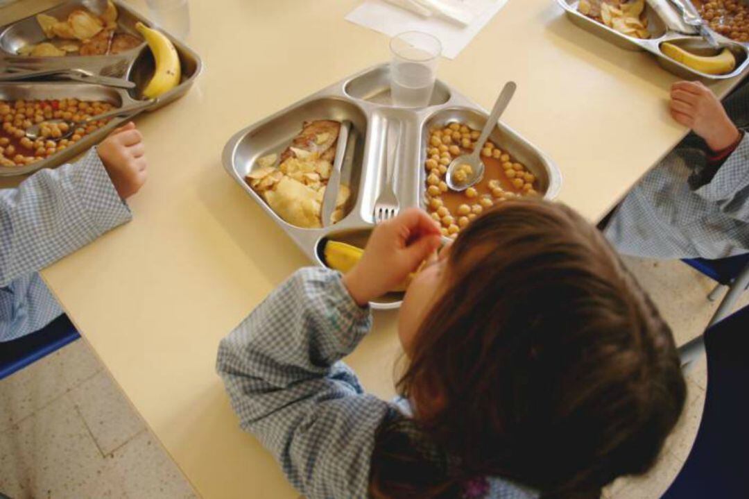 Una niña come en un comedor escolar