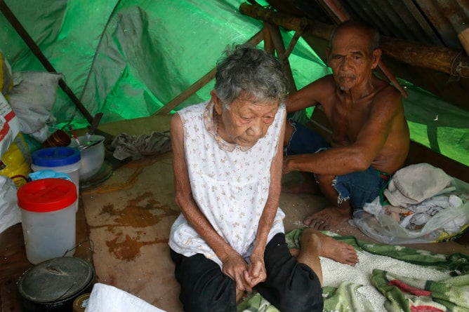 Dos personas sin hogar esperan en un refugio improvisado