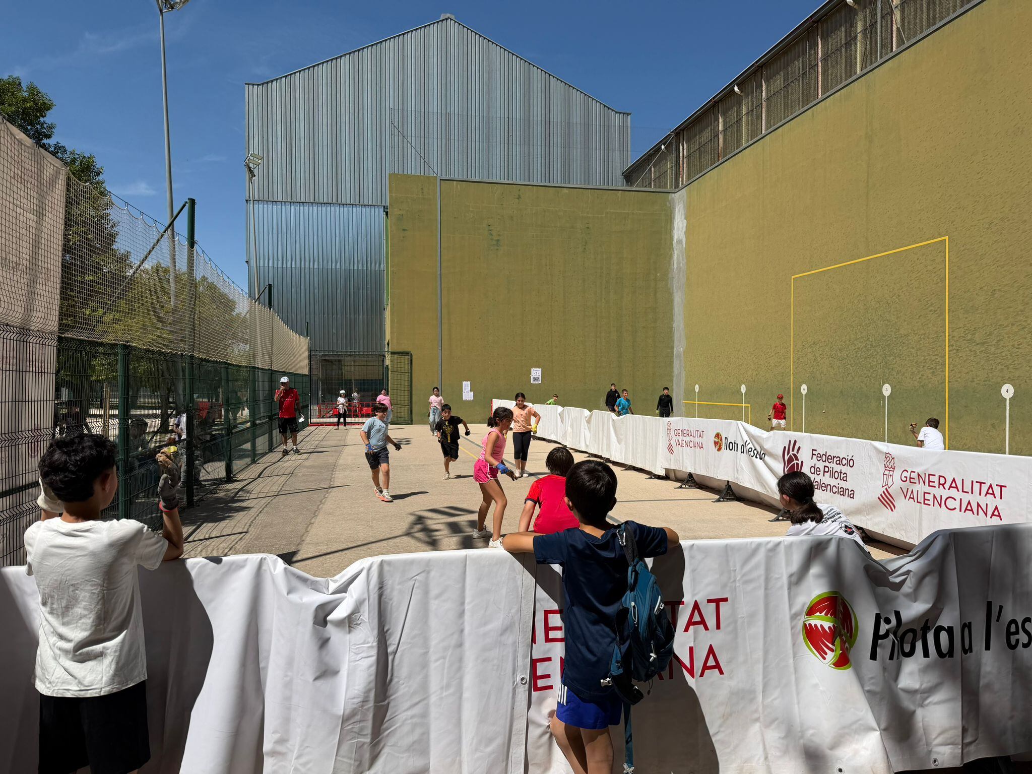 Alumnos de distintos centros educativos participan en una de las partidas de la Trobada de Pilota a l’Escola celebrada en el Polideportivo Municipal de Ontinyent