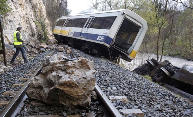 Una roca sobre la via en las inmediaciones de uno de los vagones de un tren de pasajeros, que ha descarrilado esta tarde en la localidad cántabra de Golbarzo con un balance de once pasajeros heridos, tres de ellos de gravedad.