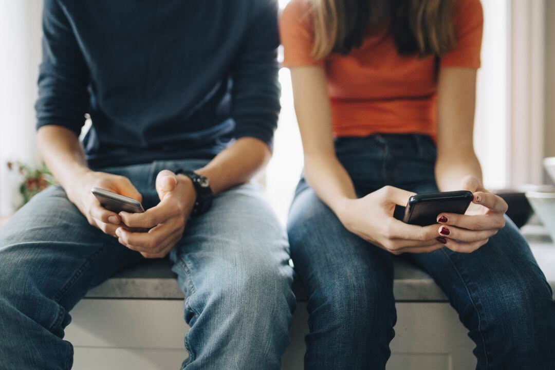 Dos jóvenes miran su teléfono móvil